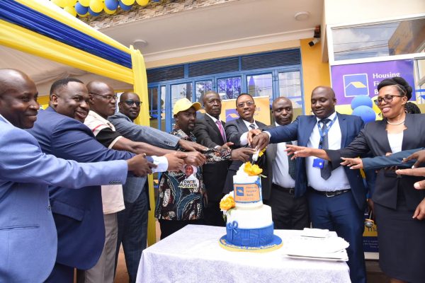 Michael Mugabi, MD of Housing Finance Bank(Center), Bosco Bainamazima, BOU (3rd from right), Nansana Town Clerk, Tandeka Festo and other HFB officials cut cake during the opening of the new branch in